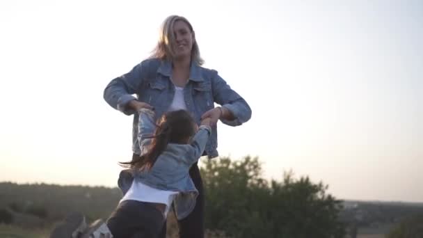 混合种族家庭 欧洲母亲和中国的女儿 花时间在公园日落 快乐的母亲抱着她的孩子 在公园里玩得很开心地旋转着 温暖的春天或夏季 — 图库视频影像