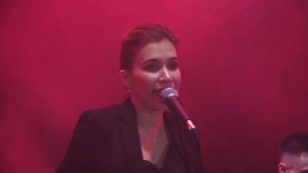 在背景中有红灯和烟雾的演出中 乐队中的一位女歌手近距离演出 — 图库视频影像