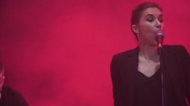 Kırmızı ışık ve duman içinde geçmiş ile gösterisi sırasında bir şarkı performans müzik grubu bir kız şarkıcı, yakın çekim.
