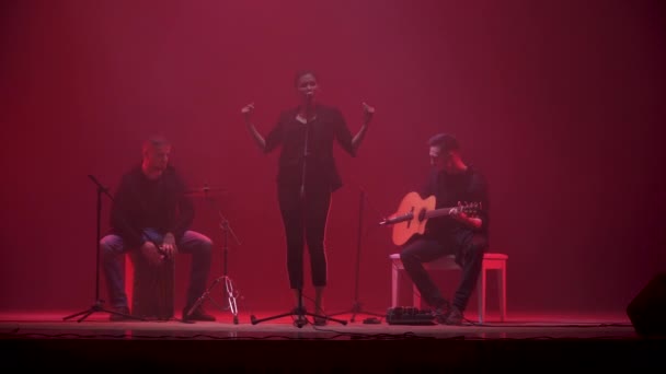 乐队在舞台上表演在红灯和烟雾背景 三位音乐家 女孩歌手 鼓手和吉他手在演出期间表演音乐 — 图库视频影像