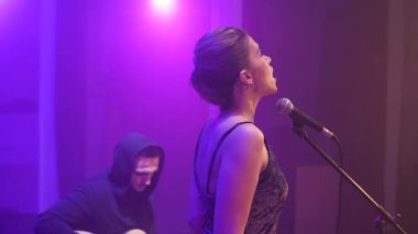 Duygusal müzik grubu ile Derma ışık ve arka plan üzerinde duman ile sahnede performans kız şarkıcı etrafında sinek Stedicam. Arkadan müzikhol ışıkların bir şarkıcı açığa