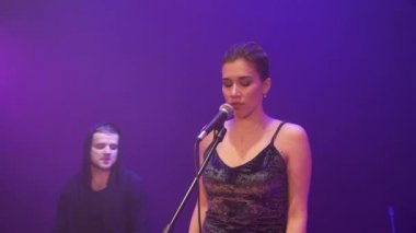 Duygusal müzik grubu ile Derma ışık ve arka plan üzerinde duman ile sahnede performans kız şarkıcı etrafında sinek Stedicam. Arkadan müzikhol ışıkların bir şarkıcı açığa