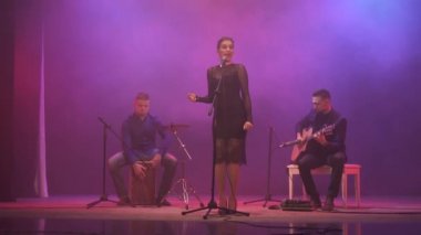 Müzik bant farklı renk ışık ve arka planda duman sahnede. Üç müzisyen - kız şarkıcı, davulcu ve gitarist müzik gösterisi sırasında gerçekleştirmek..