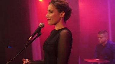 Steadicam duygusal müzik grubu ile Derma ışık ve arka plan üzerinde duman ile sahnede performans kız şarkıcı etrafında sinek
