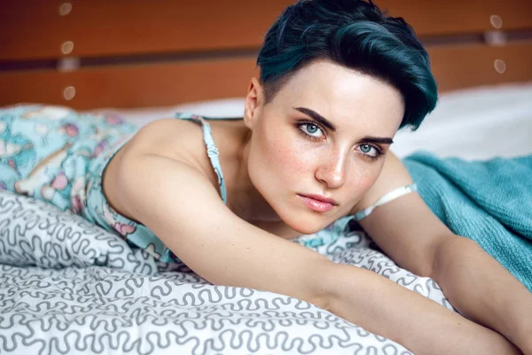 Close-up van portret van een mooie vrouw met blauwe haren liggend op bed en op zoek weg — Stockfoto