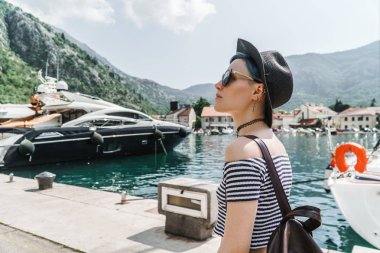 Turist kız Körfezi eski Avrupa şehri'iskele boyunca yürür ve turistik yerleri görür. arka planda birkaç Yatlar demirli