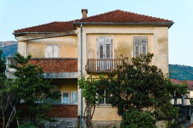 Eski terk edilmiş evde bir kırmızı kiremit çatı Avrupa tatil beldesi dağda arka planı. Satılık Emlak