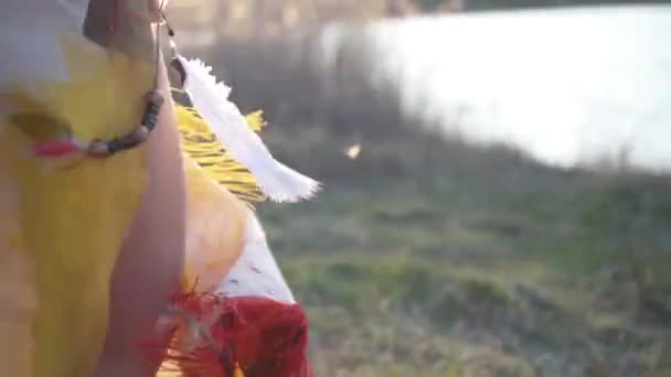 穿着土生土长的印第安人头饰 头戴五颜六色的婚纱 手里拿着青草 在夕阳西下的美丽姑娘的落日上跳舞 山核桃属 — 图库视频影像