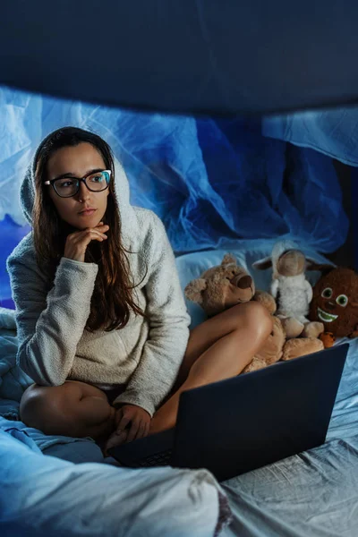Girl hikikomori with glasses at a laptop in bed
