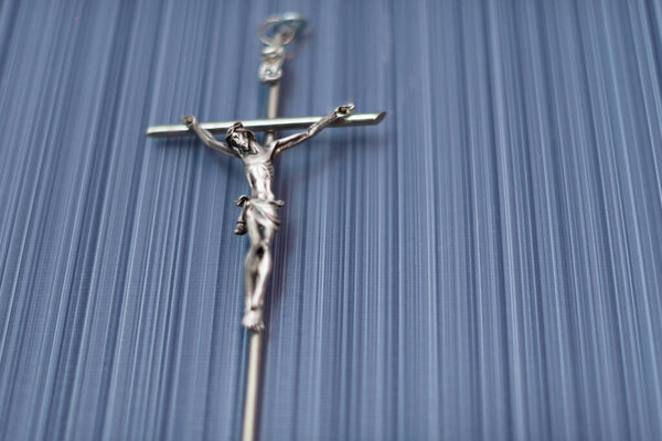 Crucifixion metal figure on a background of blue wallpaper
