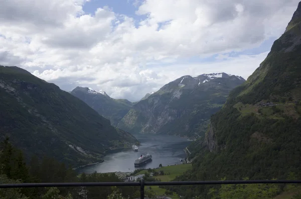 Dağlarla çevrili bir fiyort koyunda seyir gemileri. Norveç