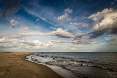 Dramatik, bulutlu mavi gökyüzü ile Polonya Hel yarımadasında uzun boş kum plaj