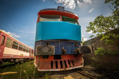 Eski dizel lokomotif tren Mezarlığı'nda yaz yeşil çimen ile ve ağaçlar arka plan ve büyük bulutlu gökyüzü