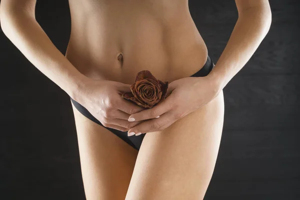 Bikini Line, Public Hair Removal and Women Health, Reproductive Health Concept, Brazilian Waxing Salon and Spa, Naked Woman in Good Shape Cover her Crotch with a rose bouquet