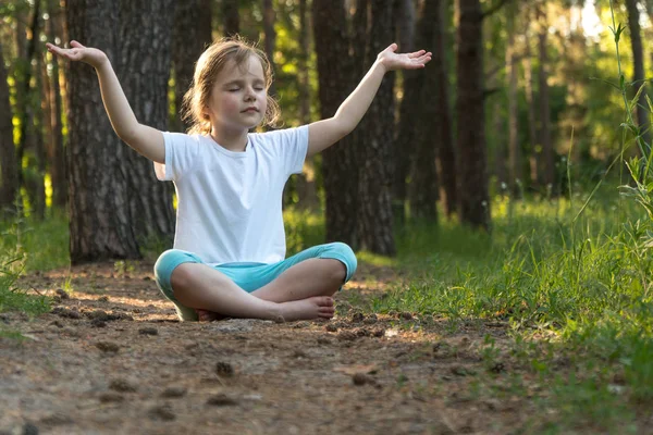 El niño está practicando yoga en el bosque . — Foto de Stock