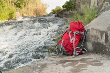 turist sırt çantası bir dağ nehri yakınında duruyor