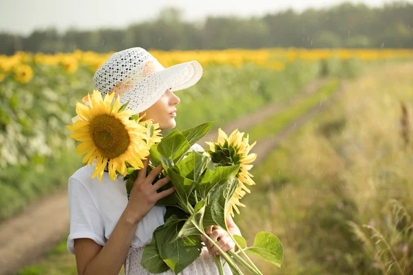 Chica en vestido blanco y sombrero blanco camina por el campo — Foto de Stock
