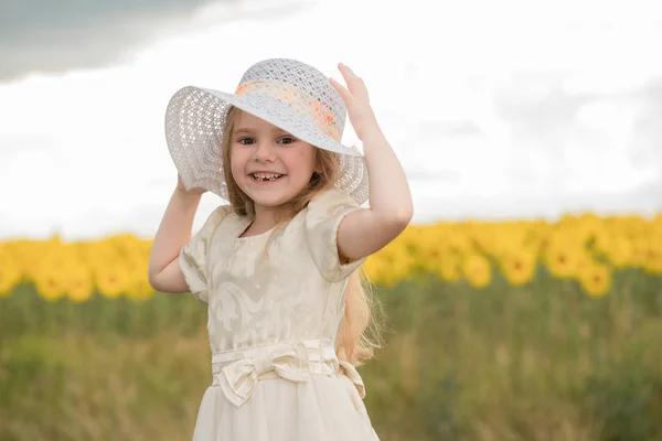 Piękne dziecko w kapeluszu na polu z kwiatami — Zdjęcie stockowe