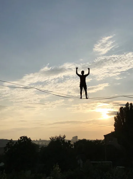 Gün batımında, Kiev, Ukrayna slackline Dengeleme genç adam silüeti