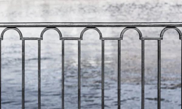 堤防とモノクロ トーンの水の背景に鉄のフェンスのクローズ アップのフラグメント — ストック写真