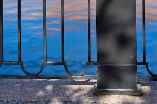 the embankment and fragment of an iron fence against the background of water closeup