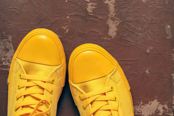 yellow fashionable gym shoes or sports boots closeup against the background of old brown skin