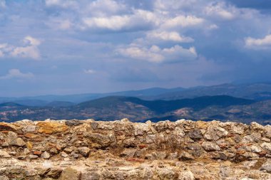 eski ve antik taş duvar ile bulutlu gökyüzü ve dağ tepeleri ufukta bir manzara arka plan karşı kapatın