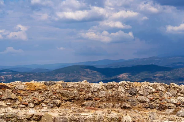eski ve antik taş duvar ile bulutlu gökyüzü ve dağ tepeleri ufukta bir manzara arka plan karşı kapatın