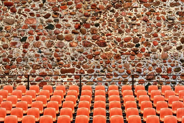 Ranghi con sedie per il pubblico sullo sfondo di un muro di pietra all'aperto — Foto Stock