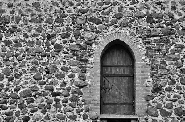 Antica parete in pietra con porta in legno in tono monocromatico — Foto Stock