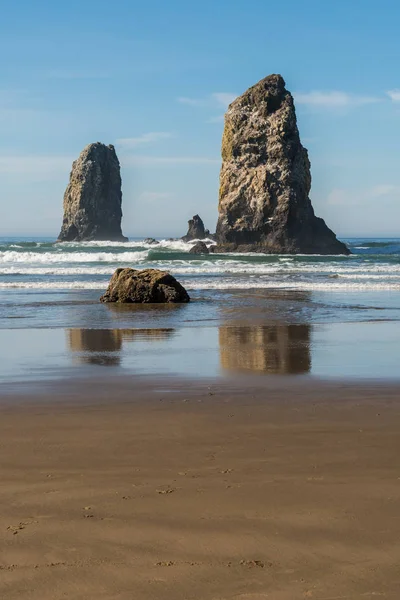 Waves crashing on vertical rocks protruding in Cannon Beach, Oregon, USA.