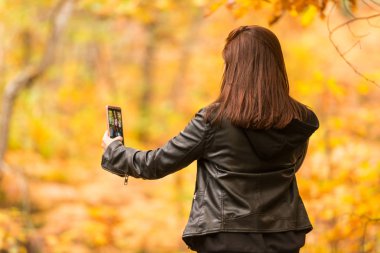 Kızıl saçlı Genç bir kadın ile cep telefonu ormandaki selfies yapıyor