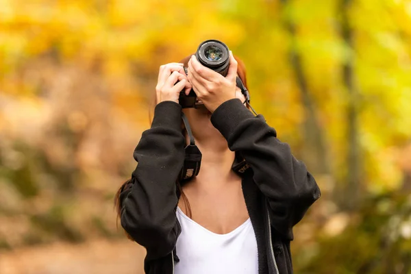 Egy fiatal nő, vöröses hajú képei, egy tükörreflexes fényképezőgépet az erdő — Stock Fotó