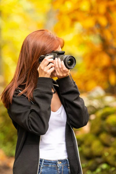 Egy fiatal nő, vöröses hajú képei, egy tükörreflexes fényképezőgépet az erdő — Stock Fotó