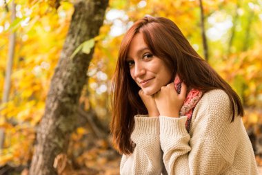 Genç bir kızıl saçlı kadın onun eşarp sonbahar ormanda ellerde ısınma 