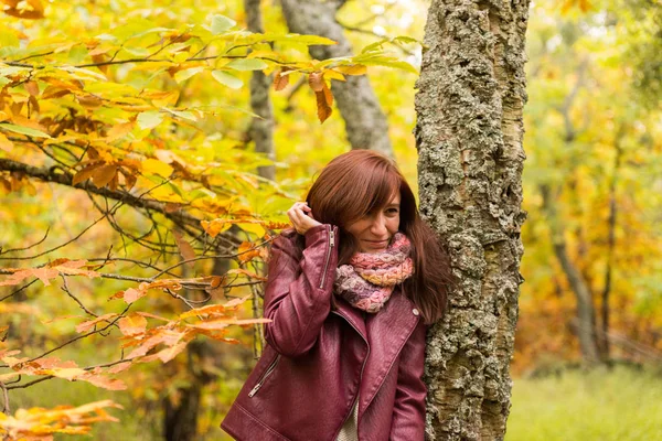 Giovane donna dai capelli rossastri disturbata dai rami di un albero in una foresta autunnale — Foto Stock