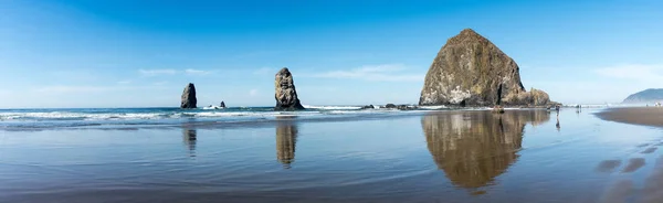Turistas y lugareños disfrutando de la playa con Haystack Rock en el fondo en Cannon beach, Oregon, EE.UU. . —  Fotos de Stock