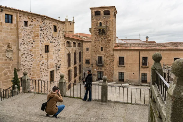 Egy pár turista fényképezni a Plaza de San Jorge, a régi város, a háttérben, Caceres, Spanyolország. — Stock Fotó