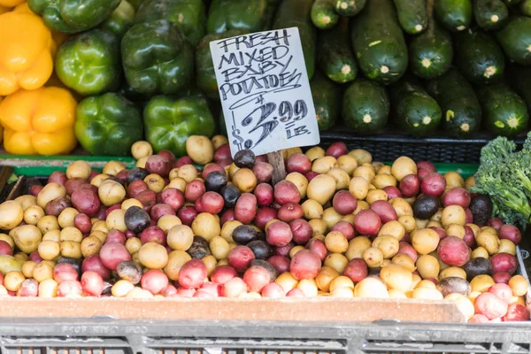 Kleurrijke baby aardappelen en andere groenten op een kraam op Pike Place Market in Seattle. — Stockfoto