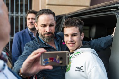 Attendees at the Vox rally make selfies with the leader, Santiago Abascal, in the Plaza de San Jorge in Caceres. clipart