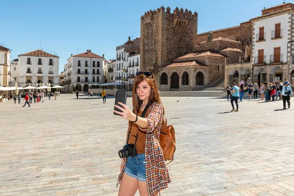 Un joven turista pelirrojo con una mochila hace un selfie en la Plaza Mayor de Cáceres — Foto de Stock