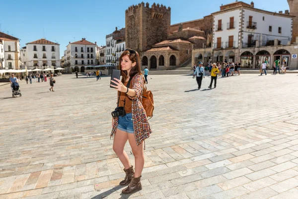 Un joven turista pelirrojo con una mochila hace un selfie en la Plaza Mayor de Cáceres — Foto de Stock