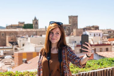 Genç bir kızıl saçlı turist arka planda Caceres eski kenti ile Galarza bakış açısı bir selfie yapar