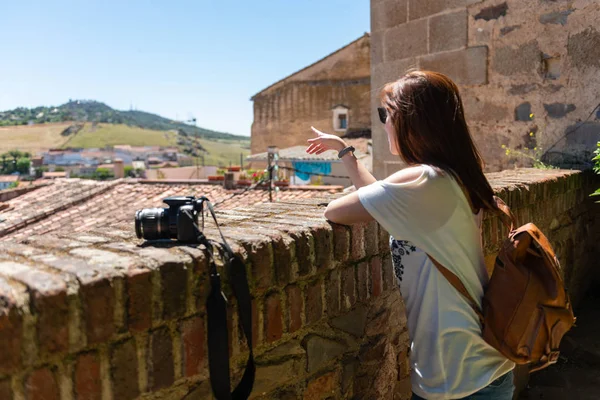 Una joven pelirroja con una mochila y una cámara observa el paisaje desde un mirador en el casco antiguo de Cáceres — Foto de Stock