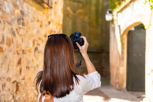 若い赤毛の観光客は、カセレスの旧市街の狭い通りの彼女のカメラで写真を撮ります — ストック写真