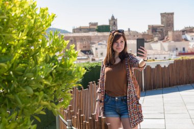 Genç bir kızıl saçlı turist arka planda Caceres eski kenti ile Galarza bakış açısı bir selfie yapar