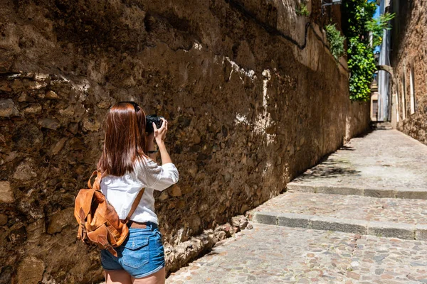 Egy fiatal vörös hajú turista fényképe a régi város szűk utcái kamerájával — Stock Fotó