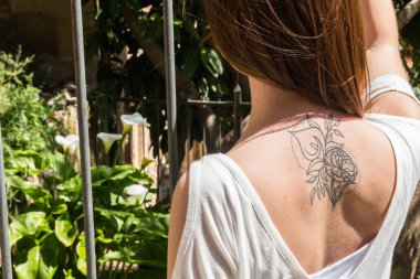 Arkadan bir Arum-Lily dövme ile genç bir kızıl saçlı turist Caceres aynı çiçekler ile bir bahçeye bakıyor