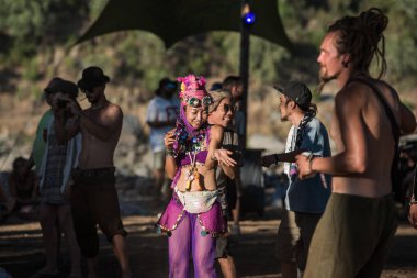 Parlak ve pembe kumaşlar giyen Asyalı kadın Lost Theory psytransce müzik festivalinde sınırsız dans