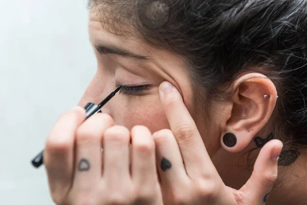 Ung kvinna applicerar eyeliner till hennes öga i Bad rums. — Stockfoto